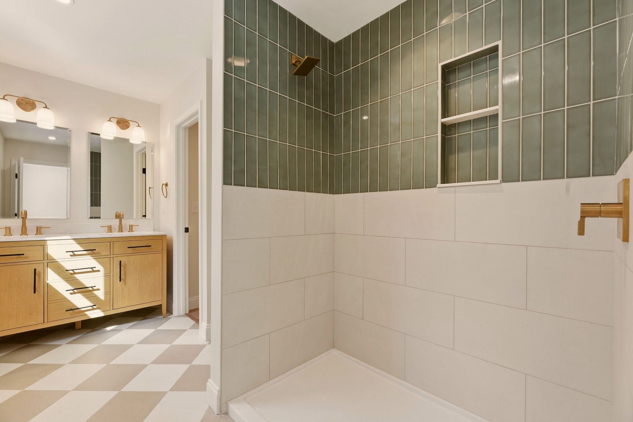 Primary bath with a white oak double vanity, checkerboard tile floor, and green tiled shower